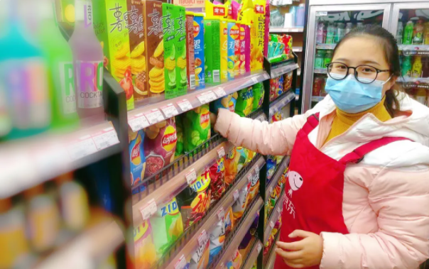 Li's wife stocks shelves in their convenience store in Chengdu, Sichuan province