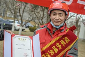 Wang Guanjun holds certificate naming him “The Honorary Resident of Jinyu Guoji Community” given to him by the resident committee of the compound he serves