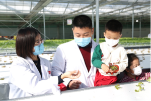 Parents show their children veggies at the plant factory